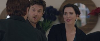 Movie still from “The Gift” (2015), directed by Joel Edgerton – A man and a woman standing next to each other in front of flowers; Close Up shot, Over the shoulder angle