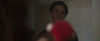 Movie still from “The Gift” (2015), directed by Joel Edgerton – A woman is smiling in a mirror with a red object in front of her; Close Up shot, Over the shoulder angle
