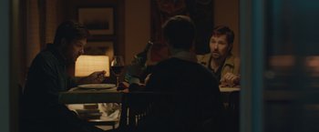 Movie still from “The Gift” (2015), directed by Joel Edgerton – Two men sitting at a table with a glass of red wine; Medium shot, Over the shoulder angle