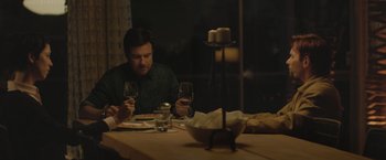 Movie still from “The Gift” (2015), directed by Joel Edgerton – A man sitting at a table with a glass of wine; Medium shot, Over the shoulder angle