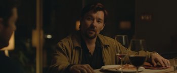 Movie still from “The Gift” (2015), directed by Joel Edgerton – A man sitting at a table with a glass of wine in front of him; Close Up shot, Over the shoulder angle