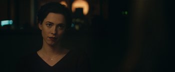 Movie still from “The Gift” (2015), directed by Joel Edgerton – A woman in a black shirt is standing in a dark room; Close Up shot, Over the shoulder angle
