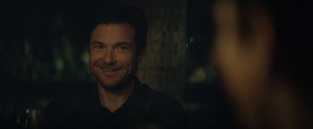 Movie still from “The Gift” (2015), directed by Joel Edgerton – A man smiling for the camera in the dark; Close Up shot, Over the shoulder angle