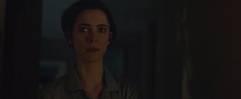 Movie still from “The Gift” (2015), directed by Joel Edgerton – A woman is looking at the camera in the dark; Close Up shot, Over the shoulder angle
