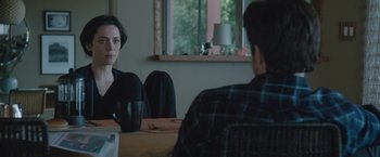 Movie still from “The Gift” (2015), directed by Joel Edgerton – Two people sitting at a dining room table; Medium shot, Over the shoulder angle