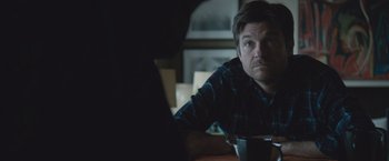 Movie still from “The Gift” (2015), directed by Joel Edgerton – A man sitting at a table with a cup in front of him; Close Up shot, Over the shoulder angle