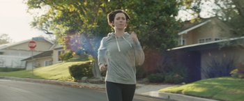 Movie still from “The Gift” (2015), directed by Joel Edgerton – A woman is running down the street with headphones on; Medium shot, Low angle