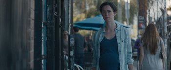 Movie still from “The Gift” (2015), directed by Joel Edgerton – A woman standing in front of a building with people in the background; Medium shot, Over the shoulder angle