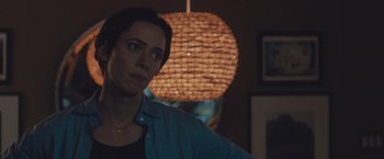 Movie still from “The Gift” (2015), directed by Joel Edgerton – A woman standing in front of a lamp in a living room; Close Up shot, Over the shoulder angle