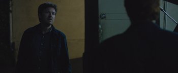 Movie still from “The Gift” (2015), directed by Joel Edgerton – A man standing in front of a door in a dark room; Close Up shot, Over the shoulder angle