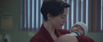 Movie still from “The Gift” (2015), directed by Joel Edgerton – A woman in a red shirt is holding a baby; Close Up shot, Over the shoulder angle