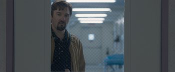 Movie still from “The Gift” (2015), directed by Joel Edgerton – A man standing in front of a chain link fence; Medium shot, Over the shoulder angle