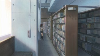 Movie still from “The Girl Who Leapt Through Time” (2006), directed by Mamoru Hosoda – A person standing in front of a book shelf in a library; Wide shot, High angle