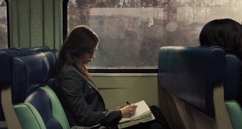Movie still from “The Girl on the Train” (2016), directed by Tate Taylor – A woman sitting on a train reading a book; Medium shot, High angle