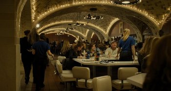 Movie still from “The Girl on the Train” (2016), directed by Tate Taylor – A group of people sitting at a table in a restaurant; Wide shot, High angle