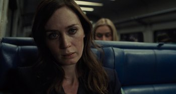Movie still from “The Girl on the Train” (2016), directed by Tate Taylor – A woman sitting on a train with another woman standing behind her; Close Up shot, Over the shoulder angle