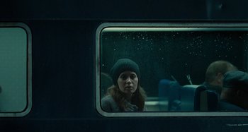 Movie still from “The Girl on the Train” (2016), directed by Tate Taylor – A woman wearing a hat looking out of a train window; Medium shot, Over the shoulder angle