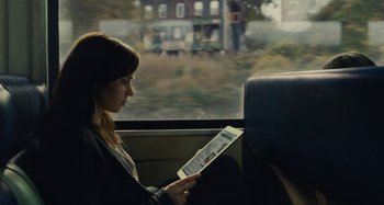 Movie still from “The Girl on the Train” (2016), directed by Tate Taylor – A woman sitting on a train looking at a tablet; Medium shot, Over the shoulder angle