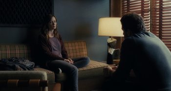 Movie still from “The Girl on the Train” (2016), directed by Tate Taylor – A woman sitting on top of a couch in front of a man; Medium shot, Over the shoulder angle