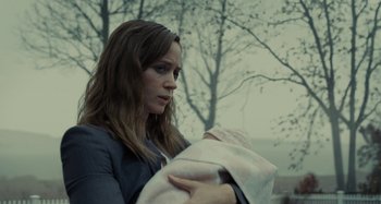 Movie still from “The Girl on the Train” (2016), directed by Tate Taylor – A woman holding a baby in her arms in front of trees; Close Up shot, Over the shoulder angle