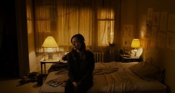 Movie still from “The Girl on the Train” (2016), directed by Tate Taylor – A woman sitting on top of a bed next to two lamps; Wide shot, High angle