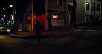 Movie still from “The Girl on the Train” (2016), directed by Tate Taylor – A person walking down a street at night; Extreme Wide shot, Over the shoulder angle