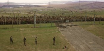 Movie still from “The Girl with All the Gifts” (2016), directed by Colm McCarthy – Two men playing baseball on a field with a fence; Extreme Wide shot, High angle