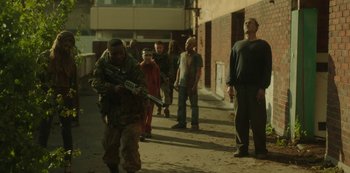 Movie still from “The Girl with All the Gifts” (2016), directed by Colm McCarthy – A group of people walking down a street with a man holding a gun; Wide shot, Low angle