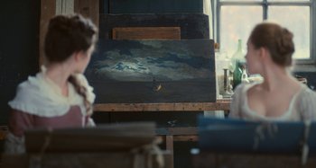 Movie still from “Portrait of a Lady on Fire” (2019), directed by Céline Sciamma – A person sitting in front of an easel in a room; Wide shot, Over the shoulder angle