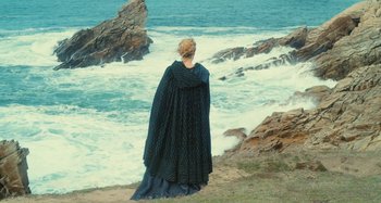 Movie still from “Portrait of a Lady on Fire” (2019), directed by Céline Sciamma – A woman standing on the beach looking out at the ocean; Extreme Wide shot, High angle