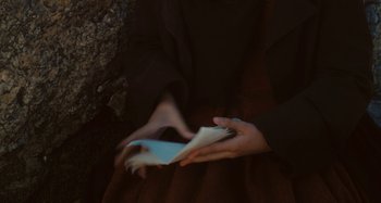 Movie still from “Portrait of a Lady on Fire” (2019), directed by Céline Sciamma – A person holding a book in their hands; Extreme Close Up shot, High angle
