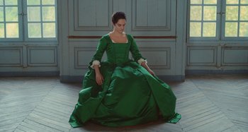 Movie still from “Portrait of a Lady on Fire” (2019), directed by Céline Sciamma – A woman in a green dress sitting on the floor; Medium shot, High angle