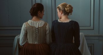 Movie still from “Portrait of a Lady on Fire” (2019), directed by Céline Sciamma – Two women are dressed in period clothing looking at each other; Medium shot, Over the shoulder angle