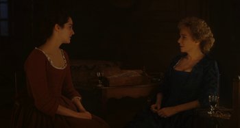 Movie still from “Portrait of a Lady on Fire” (2019), directed by Céline Sciamma – Two women are sitting in a dark room talking; Medium shot, High angle