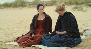 Movie still from “Portrait of a Lady on Fire” (2019), directed by Céline Sciamma – Two women sitting on the beach looking at a book; Medium shot, High angle