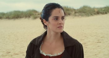 Movie still from “Portrait of a Lady on Fire” (2019), directed by Céline Sciamma – A young woman in a brown dress and a brown jacket; Close Up shot, Over the shoulder angle