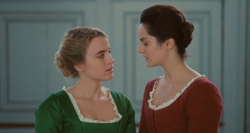 Movie still from “Portrait of a Lady on Fire” (2019), directed by Céline Sciamma – Two young women in green and red are looking at one another; Close Up shot, Over the shoulder angle