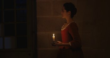 Movie still from “Portrait of a Lady on Fire” (2019), directed by Céline Sciamma – A woman holding a candle in a dark room; Medium shot, Low angle
