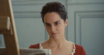 Movie still from “Portrait of a Lady on Fire” (2019), directed by Céline Sciamma – A woman looking into a mirror while wearing a red sweater; Close Up shot, Over the shoulder angle