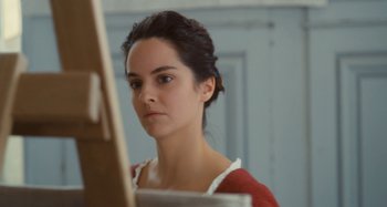 Movie still from “Portrait of a Lady on Fire” (2019), directed by Céline Sciamma – A young woman looking at the camera while standing in front of an easel; Close Up shot, Low angle