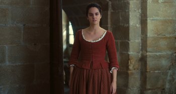 Movie still from “Portrait of a Lady on Fire” (2019), directed by Céline Sciamma – A woman in a red dress standing in front of a brick wall; Medium shot, Low angle