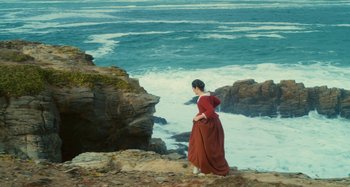 Movie still from “Portrait of a Lady on Fire” (2019), directed by Céline Sciamma – A woman standing on top of a cliff looking out at the ocean; Extreme Wide shot, High angle