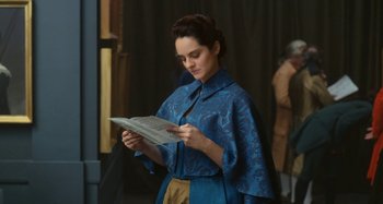 Movie still from “Portrait of a Lady on Fire” (2019), directed by Céline Sciamma – A woman in a blue dress reading a newspaper; Medium shot, Over the shoulder angle