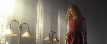 Movie still from “The Golden Compass” (2007), directed by Chris Weitz – A young girl standing next to a lamp in a room with large windows; Medium shot, Low angle