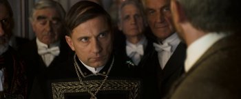 Movie still from “The Golden Compass” (2007), directed by Chris Weitz – A group of men standing next to each other in front of a wall; Close Up shot, Over the shoulder angle