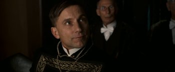 Movie still from “The Golden Compass” (2007), directed by Chris Weitz – A man in a suit and tie standing next to another man in a suit and tie; Close Up shot, Low angle