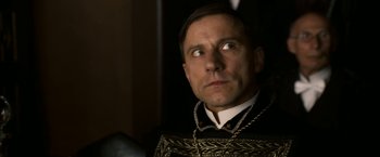 Movie still from “The Golden Compass” (2007), directed by Chris Weitz – A person wearing a suit and a necklace; Close Up shot, Low angle