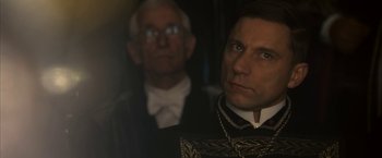 Movie still from “The Golden Compass” (2007), directed by Chris Weitz – A man in a suit and tie next to another man in a suit and tie; Close Up shot, Over the shoulder angle