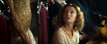 Movie still from “The Golden Compass” (2007), directed by Chris Weitz – A young girl sitting in front of an ornate chair; Close Up shot, Over the shoulder angle