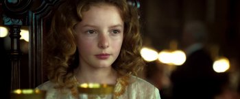 Movie still from “The Golden Compass” (2007), directed by Chris Weitz – A young girl is holding a glass of wine; Close Up shot, Over the shoulder angle